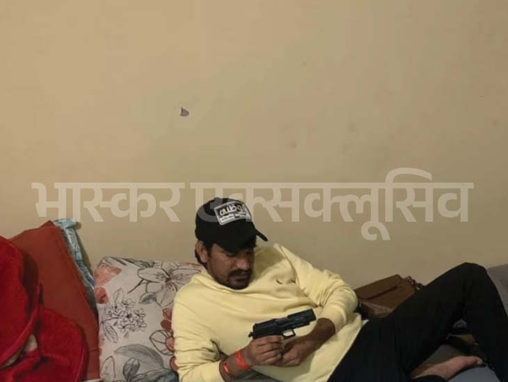 हाथ में गन लिए बिस्तर पर लेटा सचिन भिवानी।