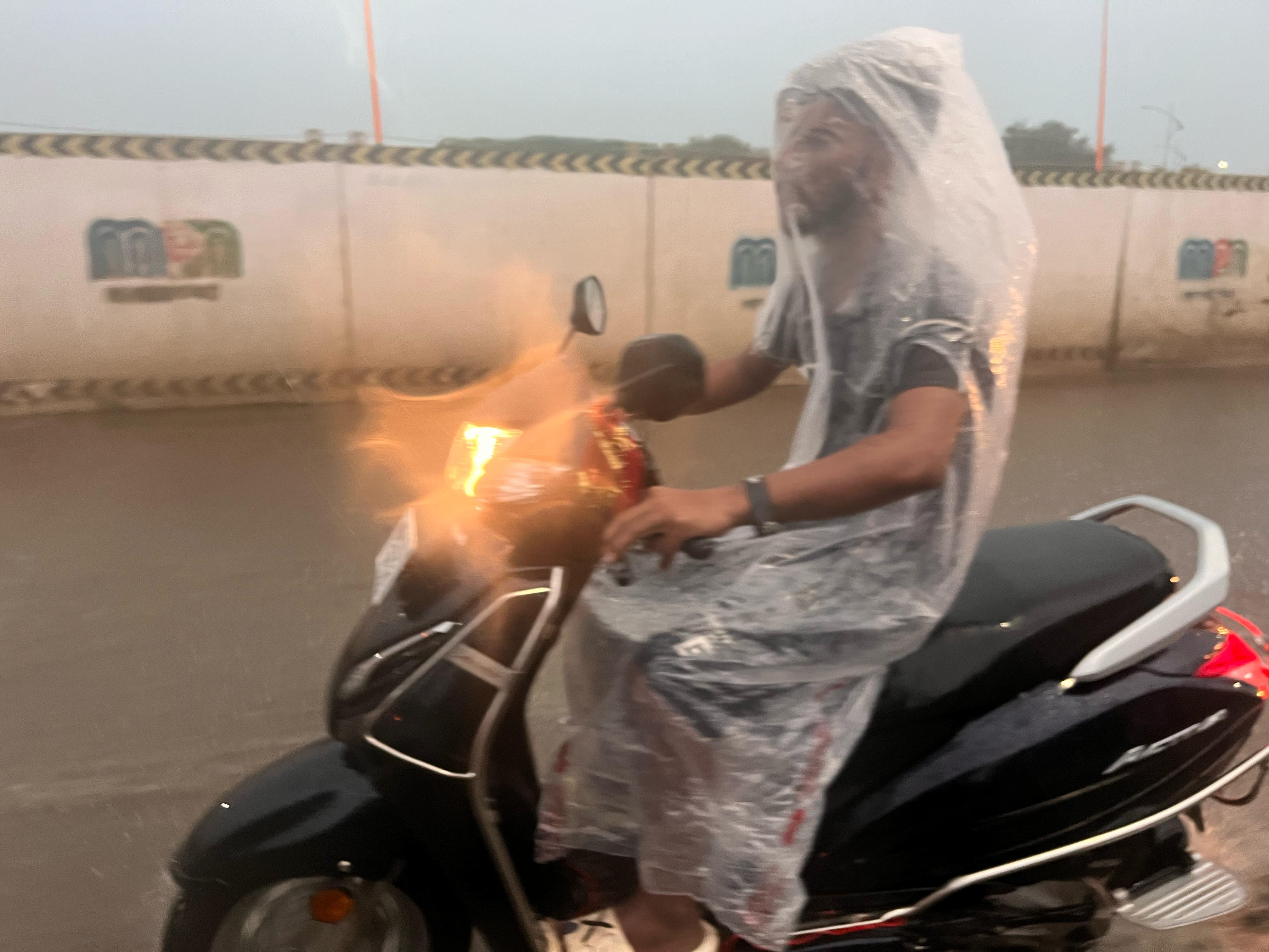 तेज बारिश में भी लोग घूमने निकलते रहे। एक एक्टिवा सवार ने बारिश से बचने के लिए कुछ यूं प्लास्टिक का जर्किन बनाकर सफर किया।