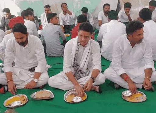 भरनी गांव में पंगत में बैठकर खाना खाते हुए पायलट। साथ में भरनी सरपंच मुकेश मीणा भी हैं।