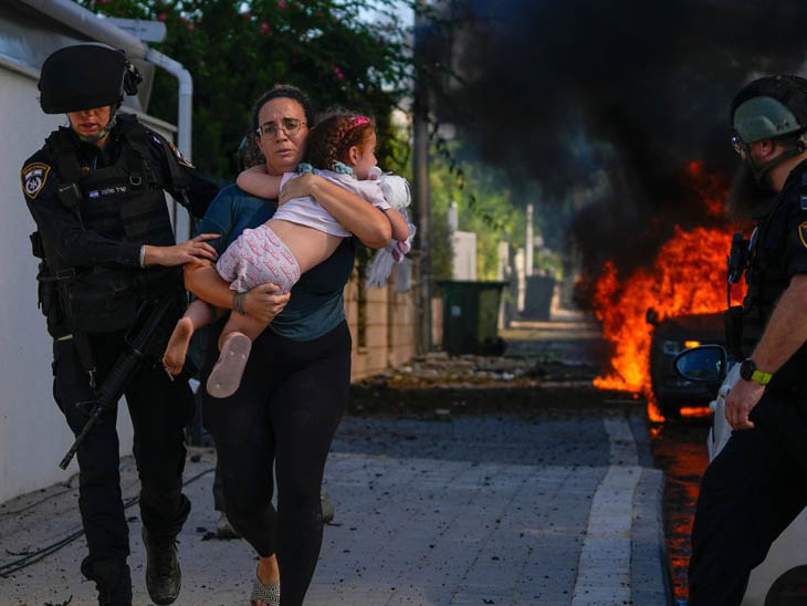 अश्कलोन में हमास का रॉकेट गिरने के बाद एक कार में आग लग गई। सुरक्षाकर्मी मां-बेटी को वहां से बाहर निकालते नजर आए।