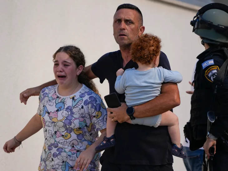 तेल अवीव में हमास के हमलों के बीच एक शख्स अपने बच्चों को सुरक्षित स्थान पर ले जाता हुआ नजर आया।