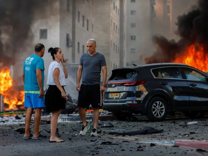 इजराइल के अश्कलोन शहर में हमास के हमलों के बाद तबाही देखते लोग।