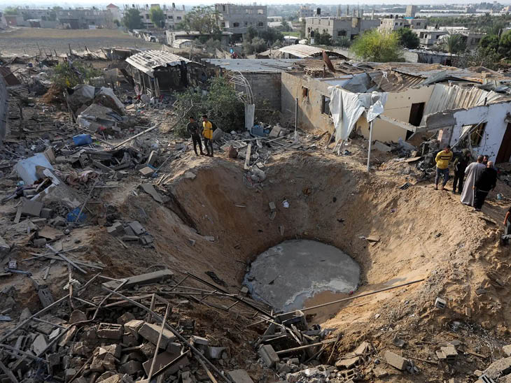 गाजा के खान यूनिस में इजराइल के हमले के बाद एक बड़ा गड्ढा हो गया।