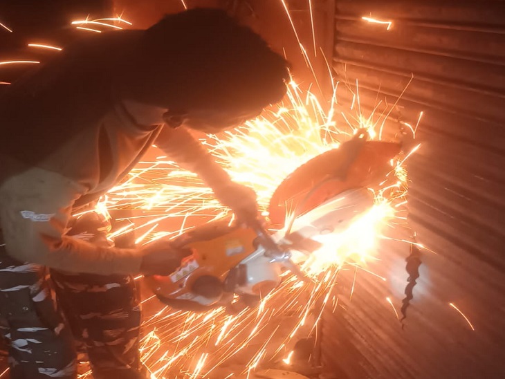 दुकान के शटर को काटता युवक।