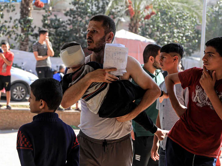 खान यूनिस के नासेर अस्पताल में बच्चे को इलाज के लिए लेकर पहुंचा व्यक्ति।