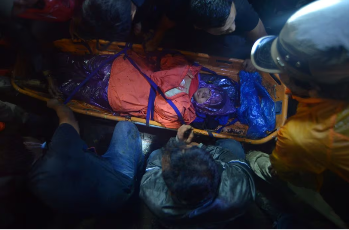 मारापी वोल्केनो में विस्फोट होने के बाद वहां से बचाई गई पर्वतारोही को अस्पताल ले जाते हुई रेस्क्यू टीम