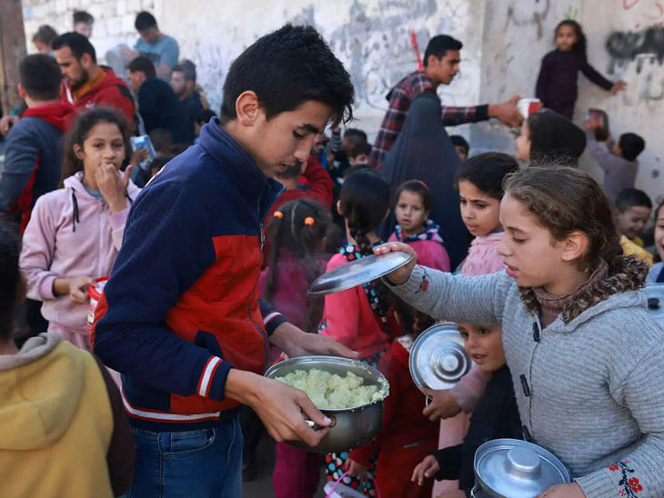 राफा बॉर्डर पर फूड डोनेशन पॉइन्ट पर विस्थापित हुए फिलिस्तीनी बच्चे खाना ले रहे हैं।