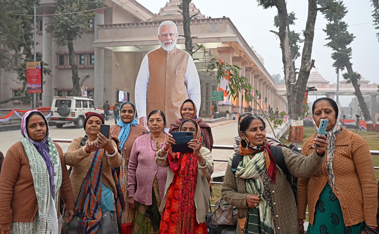 रेलवे स्टेशन के बाहर महिलाएं पीएम मोदी की तस्वीर के साथ सेल्फी लेती दिख रही हैं।