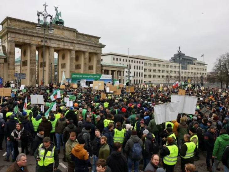 बर्लिन में ब्रैंडेनबर्ग गेट के पास हजारों किसान सरकार के खिलाफ नारेबाजी कर रहे हैं।