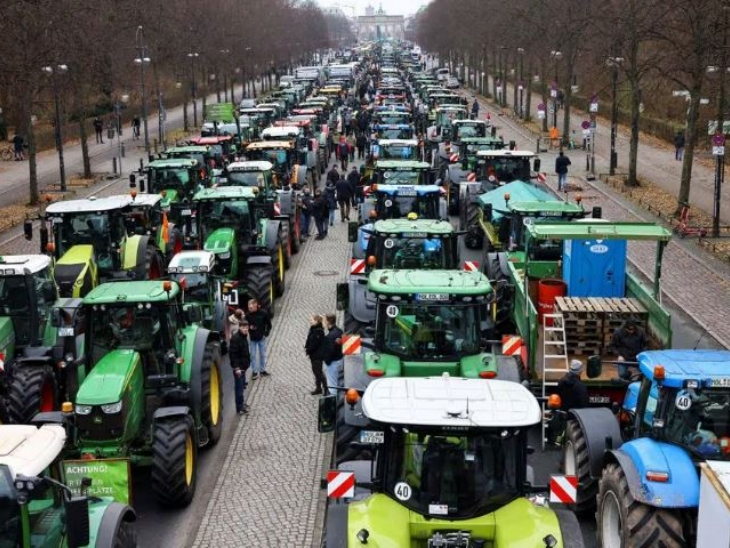 बर्लिन के एतिहासिक ब्रांडेनबर्ग गेट के बाहर ट्रैक्टरों की कतार है।