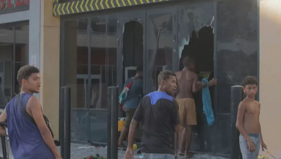 पोर्ट मोरेस्बी में लोगों ने एक दुकान में लगे कांच के दरवाजे तोड़ दिए। अंदर घुसकर सामान चोरी कर लिया।