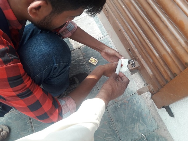 दुकान को सील करता निगम कर्मी। - Dainik Bhaskar