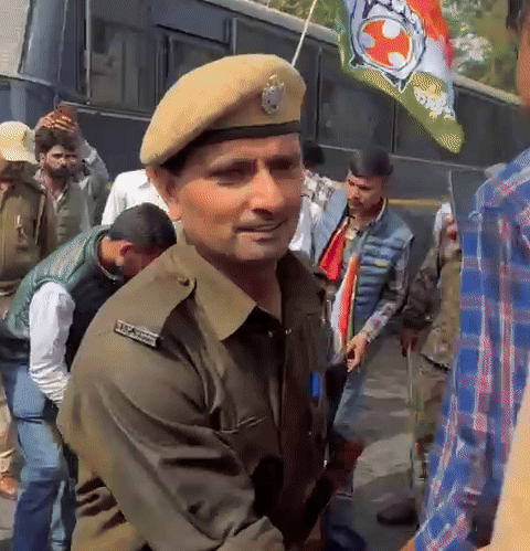 पानी की बौछारों और लाठीचार्ज से घायल एक कार्यकर्ता जमीन पर बैठ गया, जिसे साथियों ने संभाला।