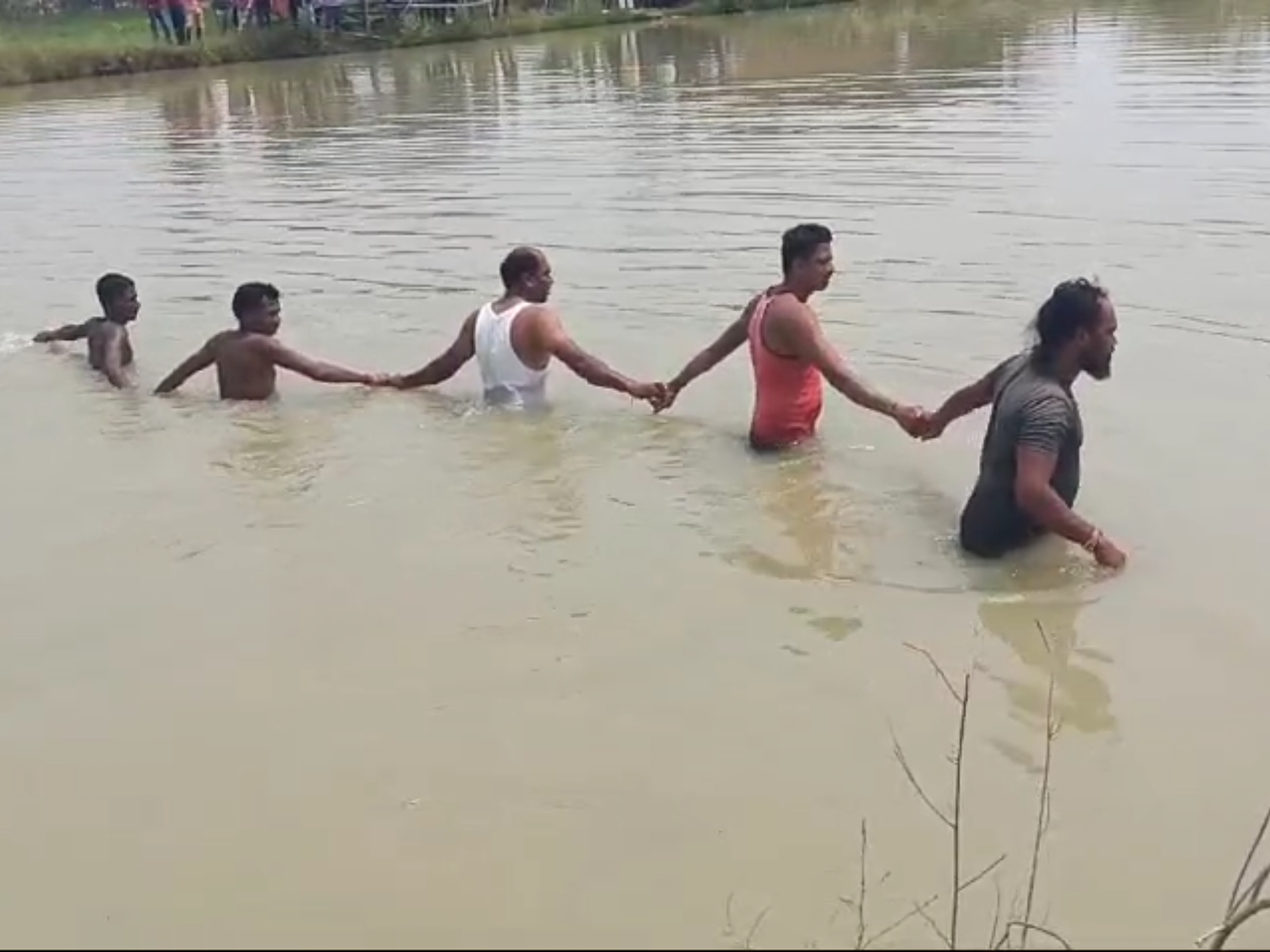 तालाब में बच्चों को ढूंढते ग्रामीण।