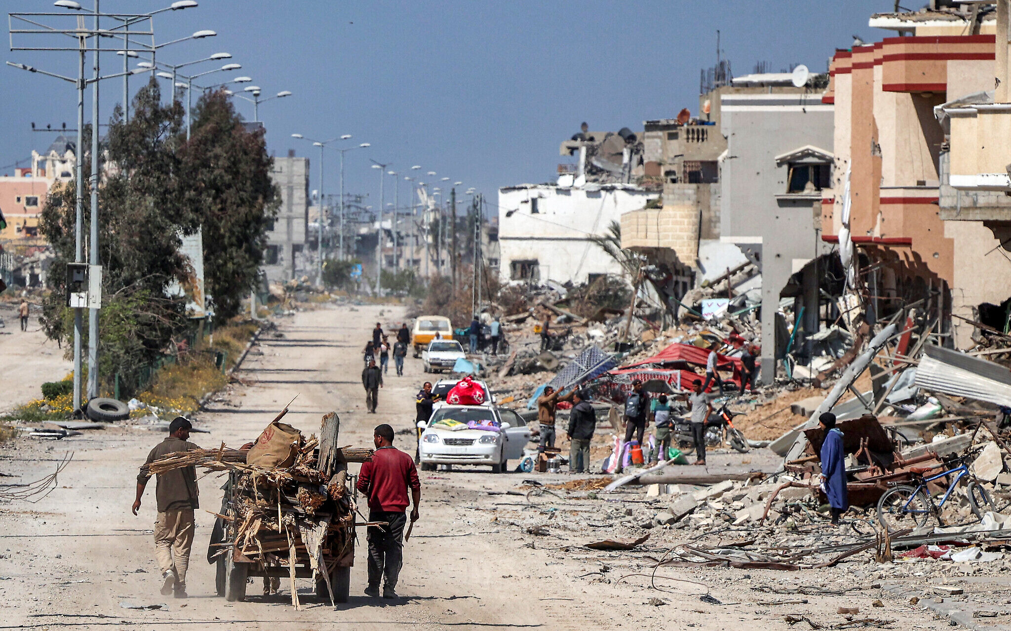 दो लोग गधा गाड़ी पर अपने घर का मलबा ले जाते हुए।