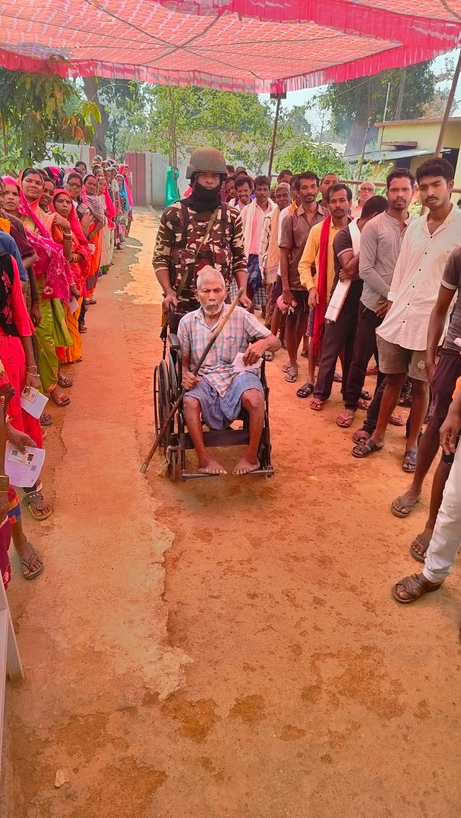 कोंडागांव में एक बूथ पर बुजुर्ग को व्हील चेयर पर मतदान के लिए लेकर जाता जवान।