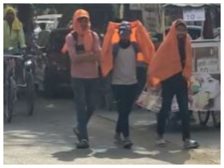 तेज धूप से बचने के लिए गमछा का इस्तेमाल करते लोग।