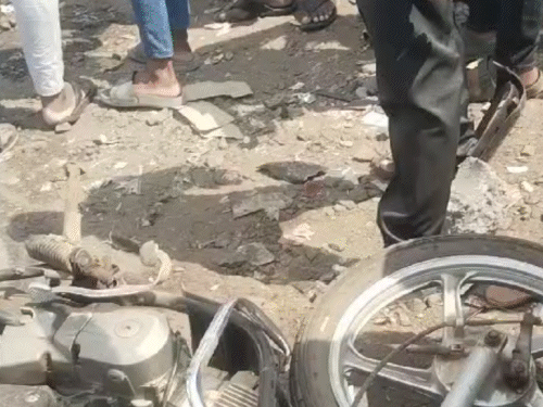 हादसे के बाद भीड़ जमा हो गई, क्षतिग्रस्त कार और बाइक सड़क पर पड़ी हुई।
