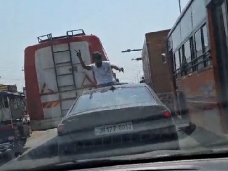 तस्वीर में दिख रहा है कि एक काले रंग की कार नंबर JH-17-P-0012 की छत पर लड़का डांस कर रहा है।
