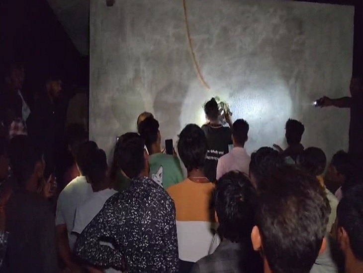 दीवार और दरवाजे को तोड़ते हुए लोग और मजूद पुलिस