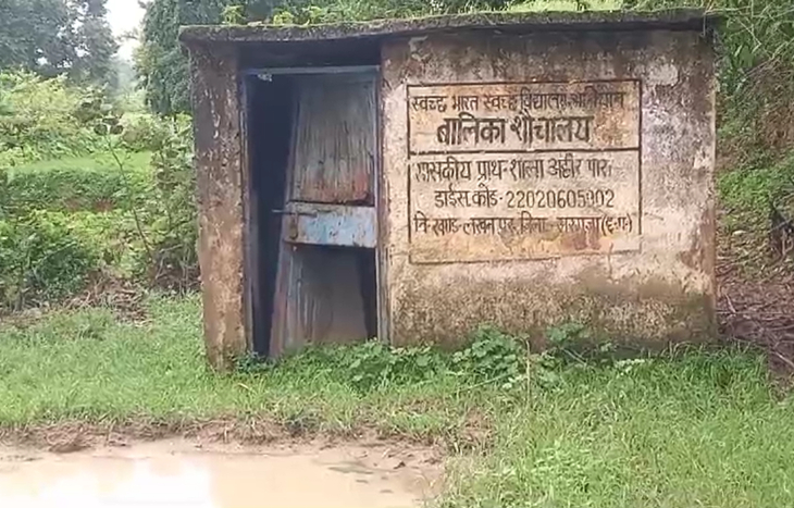 ये स्कूल के शौचालय का हाल है। दीवार पर स्वच्छ भारत विद्यालय अभियान लिखा है। टॉयलेट जर्जर हालत में है, दरवाजा टूटा है और सामने बारिश का पानी भरा है।