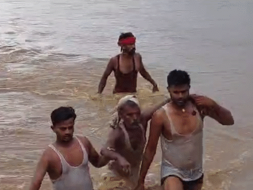 गया में फल्गु नदी में डूब रहे एक शख्स को बाहर लाते लोग।