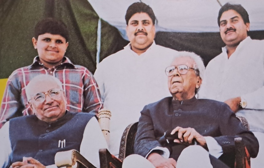 चौधरी देवीलाल,अपने सबसे बड़े बेटे ओमप्रकाश चौटाला के साथ कुर्सी पर बैठे हुए। पीछे दुष्यंत चौटाला, अजय चौटाला और अभय चौटाला। (बाएं से दाएं)