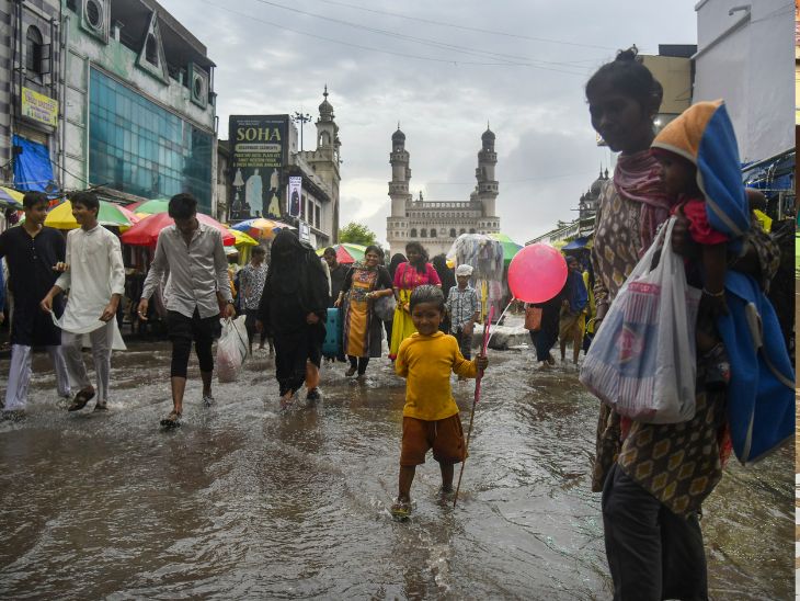 People crossing the road amid waterlogging in Hyderabad.