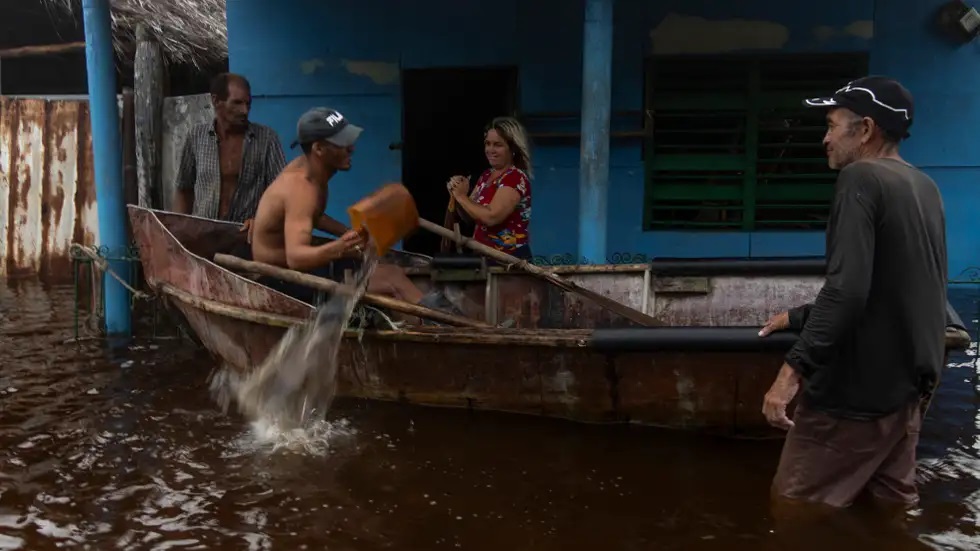 Due to heavy rains people's houses were flooded. After this, a person is taking out water from the house in a boat.