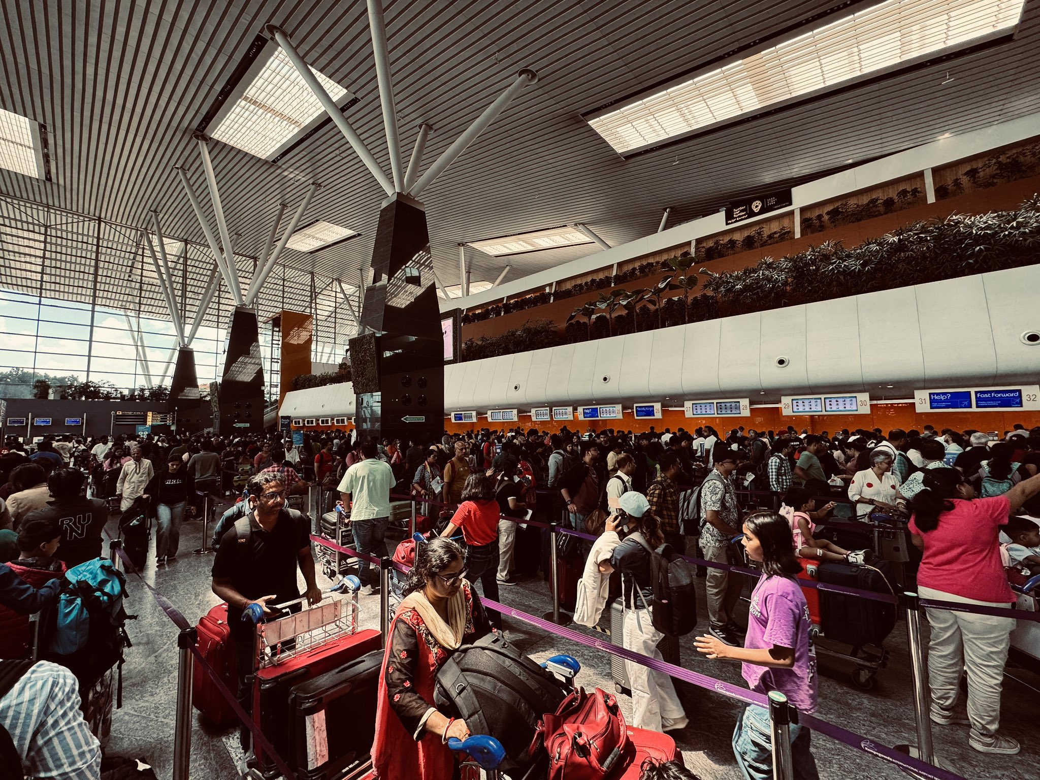 There is a crowd of passengers in front of IndiGo counters at Campagouda International Airport in Bengaluru.