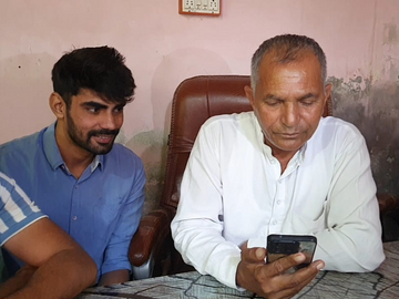 डीग गावचे सरपंच रोहताश नैन एचएसएससी अध्यक्ष फोनवर बोलत आहेत.
