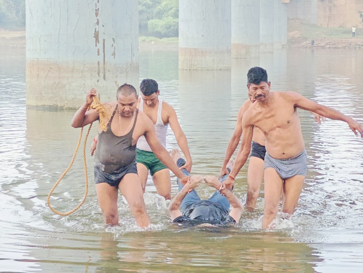 युवक के शव को नदी से बाहर निकालते हुए - Dainik Bhaskar