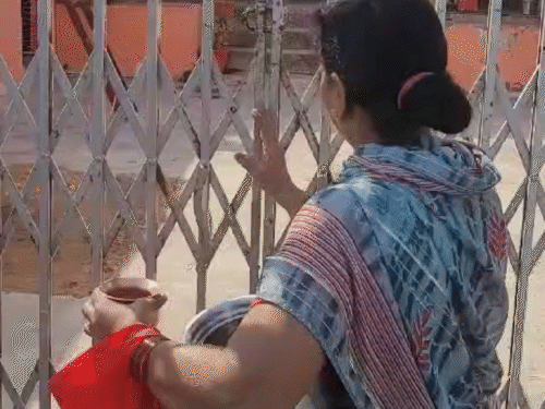 मंदिर का चैनल खोलकर अंदर जाती महिला।