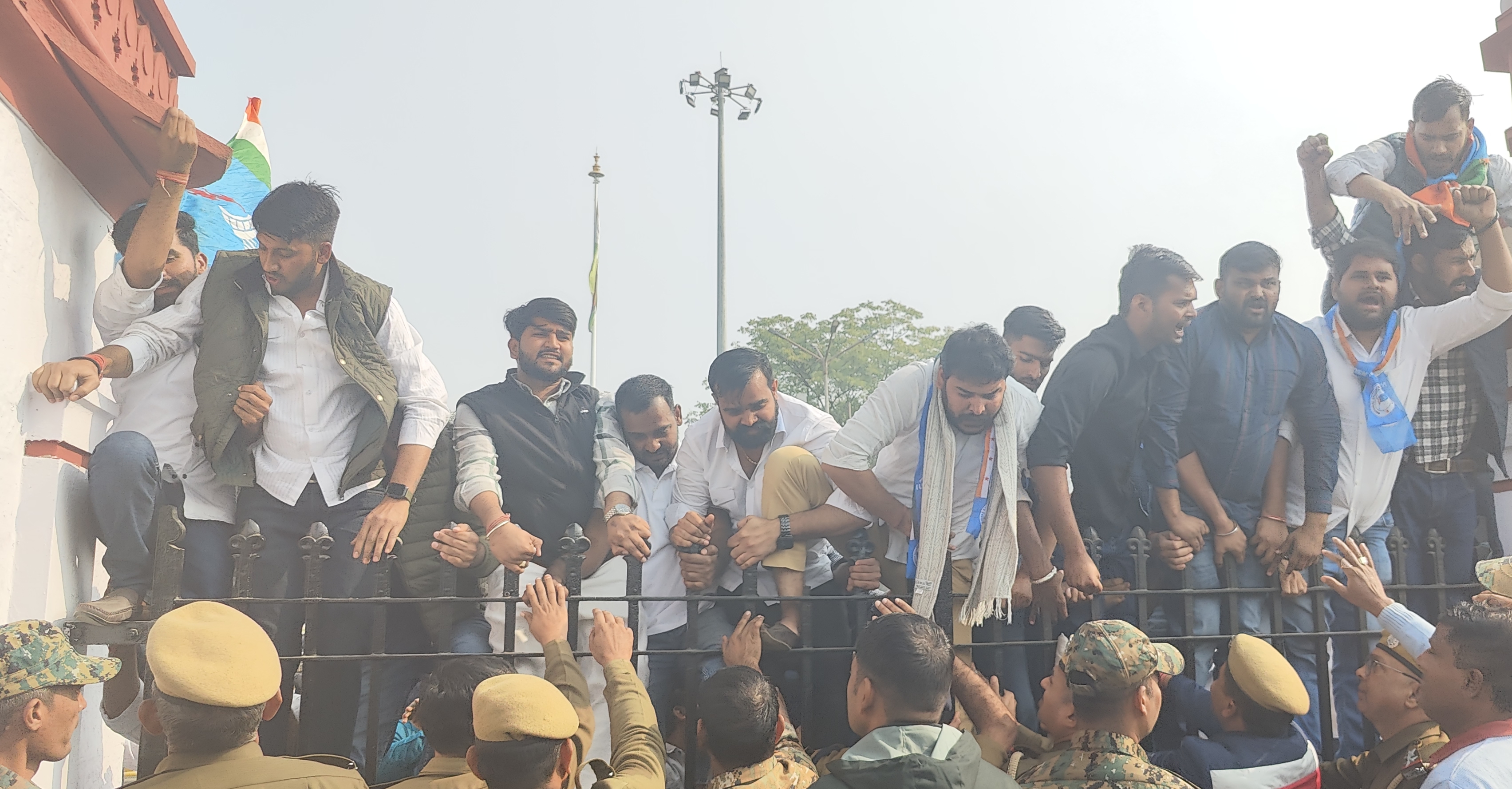 राजस्थान यूनिवर्सिटी के मुख्य द्वार पर चढ़कर विरोध जताते NSUI कार्यकर्ता।