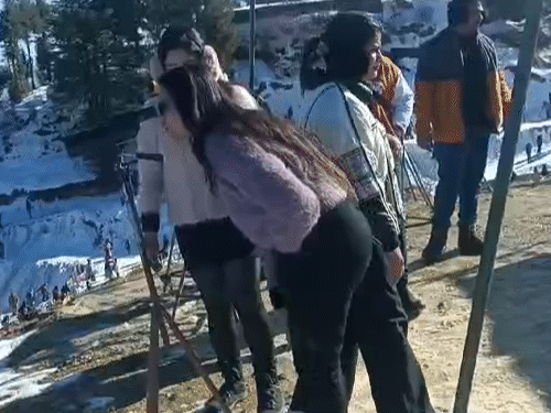 Tourists looking at the snow covered Himalayan range through binoculars at Mahasu Peak adjacent to the famous tourist destination Kufri.