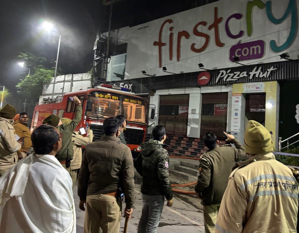 वाराणसी के सिगरा थाने के सामने बिल्डिंग में ऊपरी तल पर आग बुझने के बाद बेबी-प्रोडक्ट शोरुम में धुंआ उठने के बाद जांच करते फायर और पुलिसकर्मी।