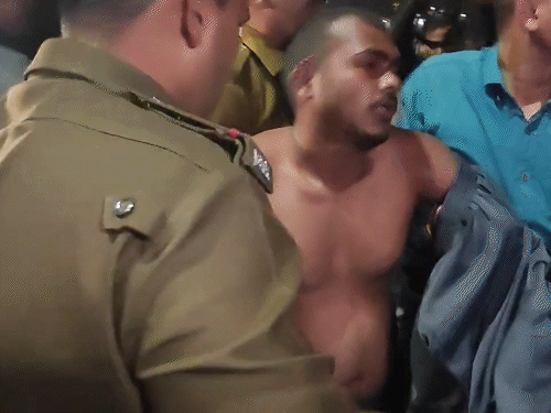 प्रदर्शनकारी शिक्षक को सड़क उठाकर ले जाती हुई पुलिस। शिक्षक के शरीर पर कपड़े नहीं थे।