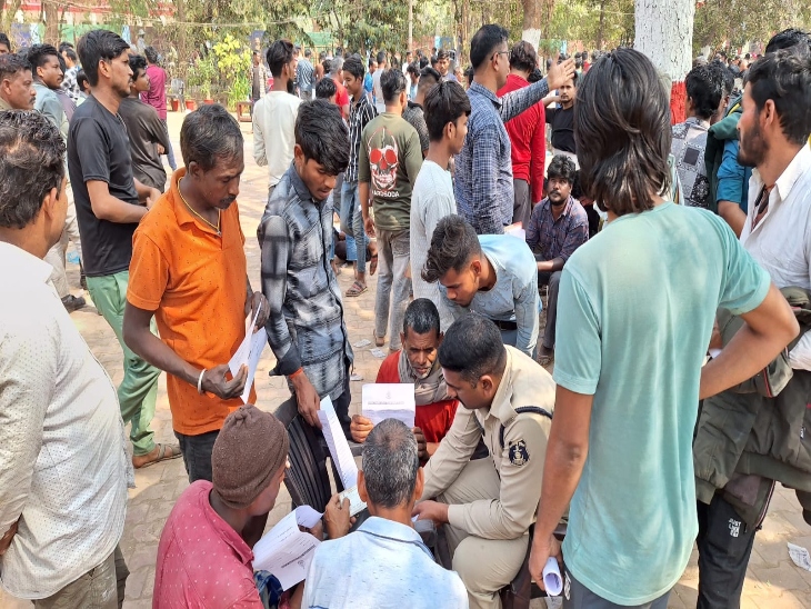 आधार कार्ड दिखाकर अपना फॉर्म भरवाते लोग।