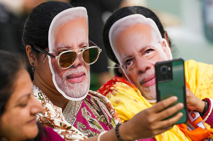 दिल्ली के आरके पुरम में एक रैली के दौरान प्रधानमंत्री नरेंद्र मोदी के मुखौटे पहनी BJP की महिला कार्यकर्ता।