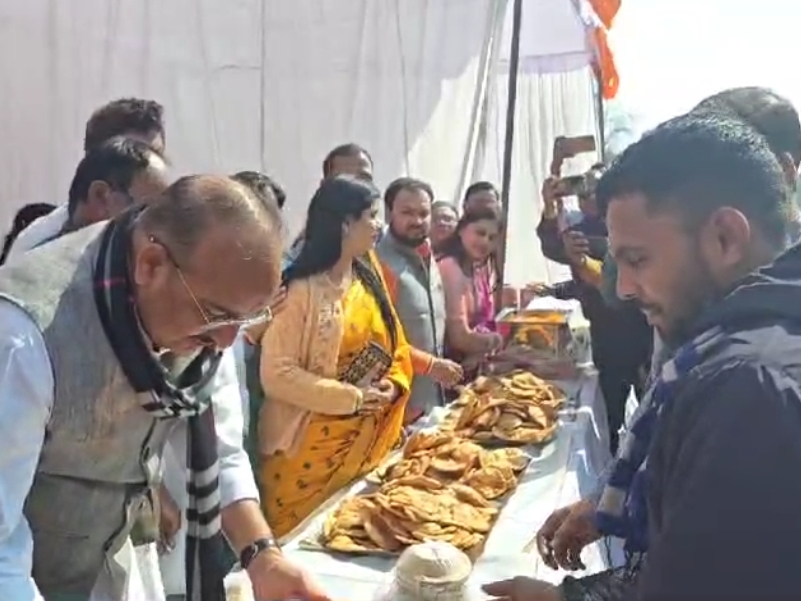 श्रद्धालुओं को प्रसाद वितरण करते यूपी सरकार के मंत्री दिनेश सिंह।