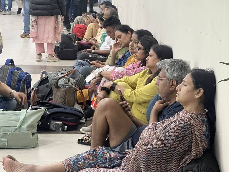 रविवार रात प्रयागराज के बमरौली स्थित एयरपोर्ट पर यात्री फ्लाइट के इंतजार में जमीन पर बैठे रहे।