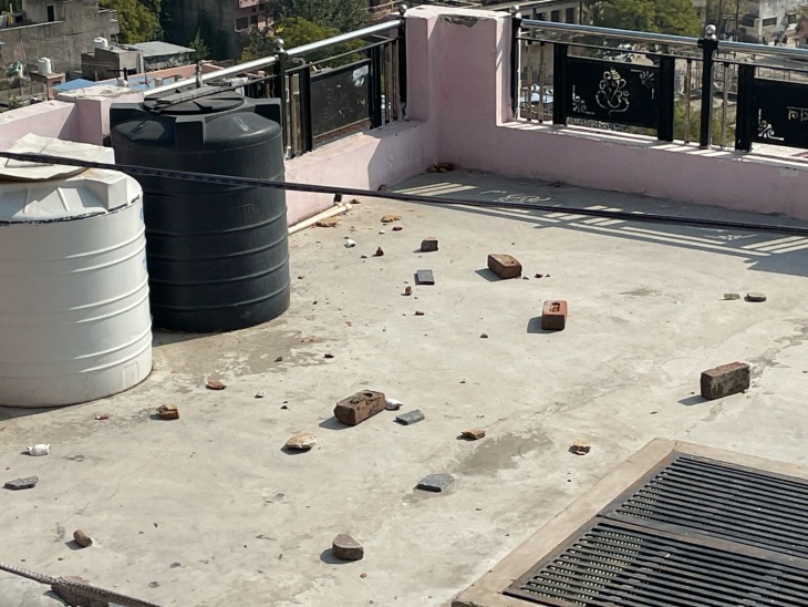 एक घर की छत पर फेंक गए ईंट और पत्थर। मौके पर शांति है और पुलिस बल तैनात है।