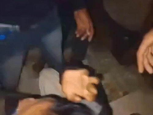 भीड़ के हमले के बाद नीचे बैठी महिला पुलिसकर्मी को घेरकर खड़े रहे लोग।