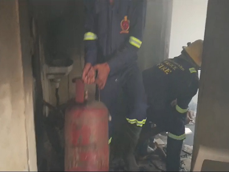 घर से गैस सिलेंडर को बाहर निकालते दमकल कर्मी