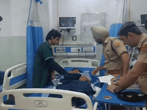 अस्पताल में घायल आशीष तिवारी का बयान लेते पुलिस अधिकारी।