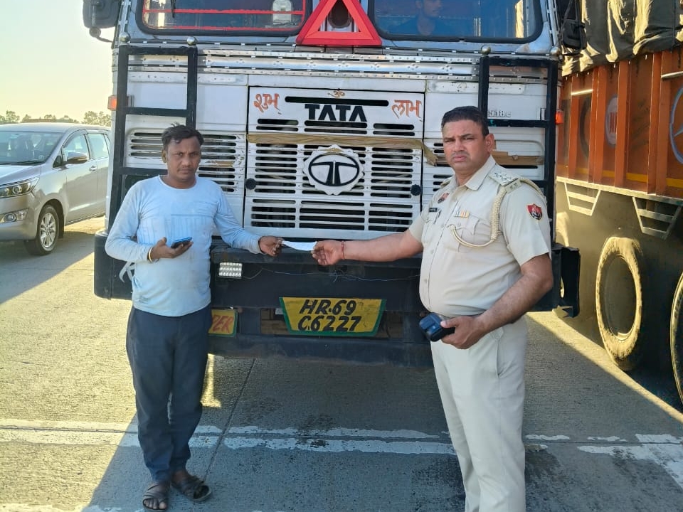 चालान काट ड्राइवर को पर्ची देते हुए पुलिसकर्मी।