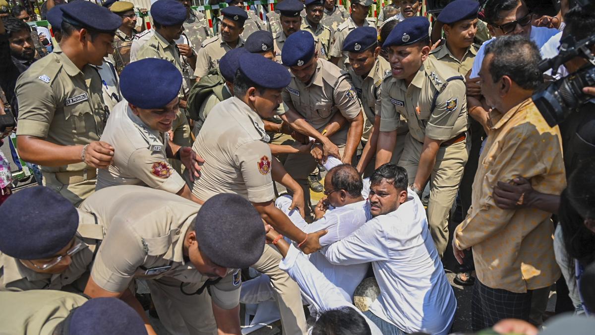 विधानसभेच्या पूर्व प्रवेशद्वारासमोर निदर्शने करणाऱ्या काँग्रेस आमदारांना पोलिस हटवत आहेत.