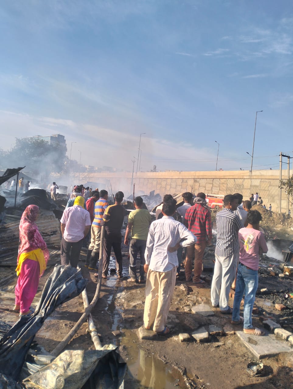 गुरुग्राम में अपने जले हुए आशियाने को देखते झुग्गियों में रहने वाले लोग।