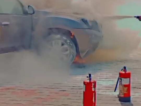 अग्निशमन यंत्र से आग बुझाते हुए पार्किंग कर्मचारी।