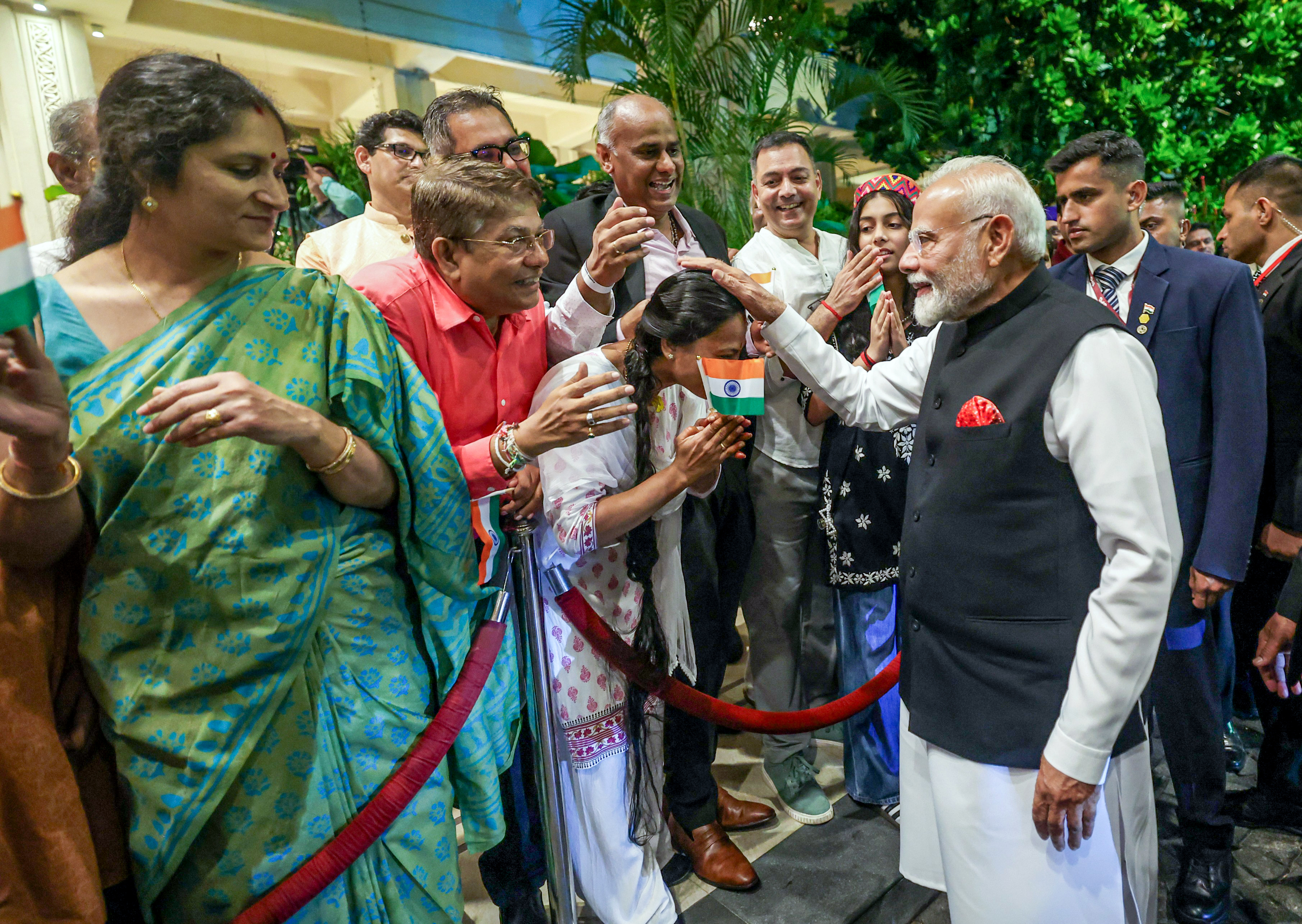 एयरपोर्ट पर PM मोदी का स्वागत करते हुए भारतीय समुदाय के लोग।